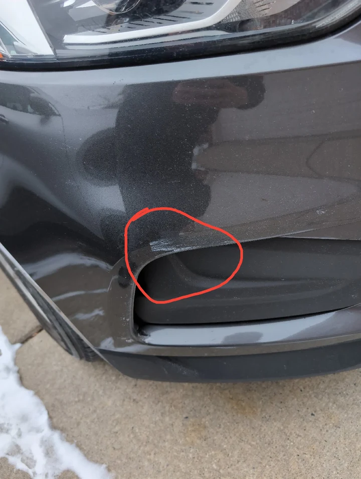 Original photograph from sample report page 3, with the front bumper scratch circled in red.