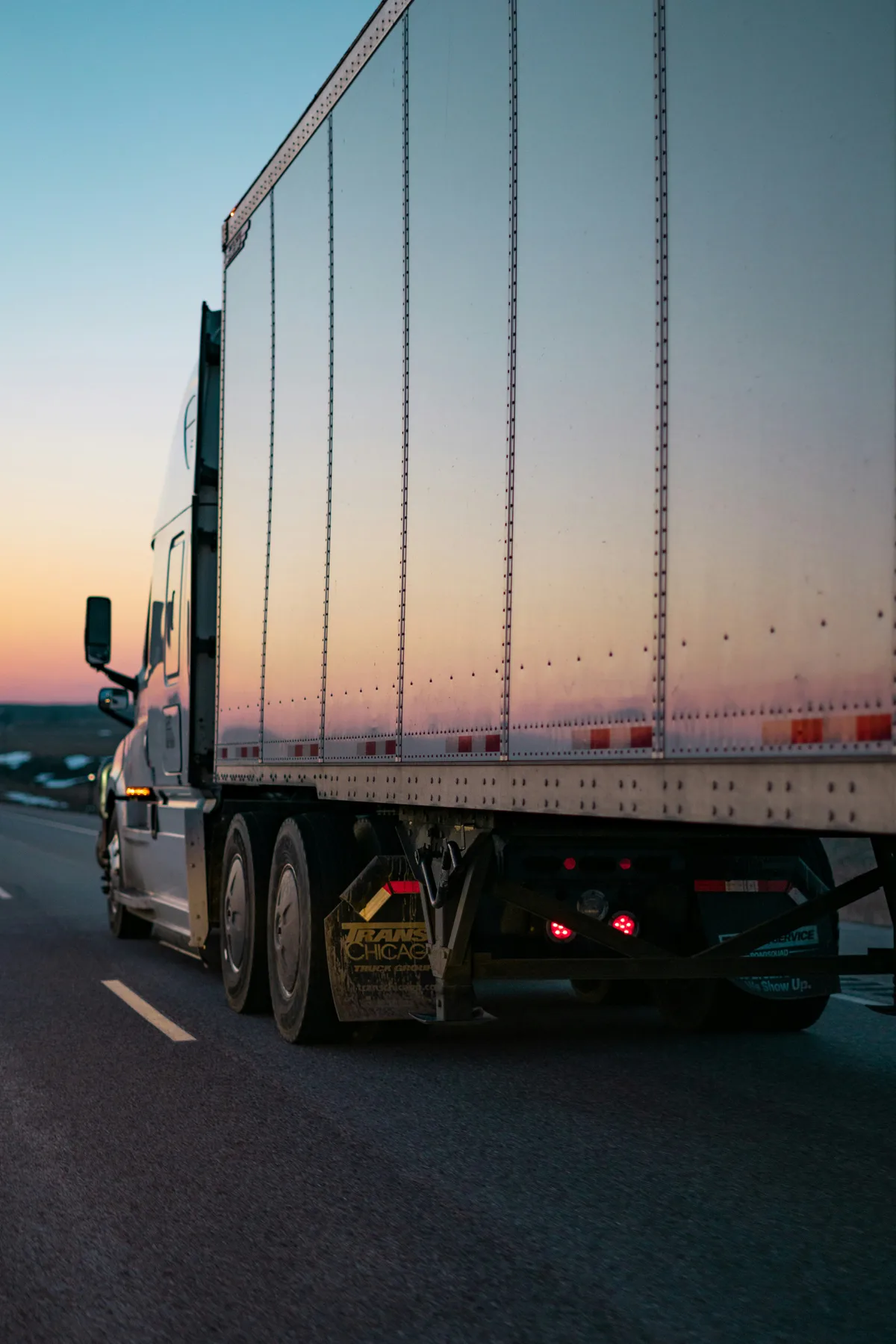 A freight truck on the road at sunset.